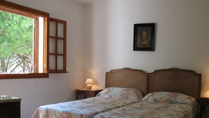 A bedroom with two beds, a window, a lamp, and a framed picture on the wall. - 2 bedroom apartment, Roche (Roche)
