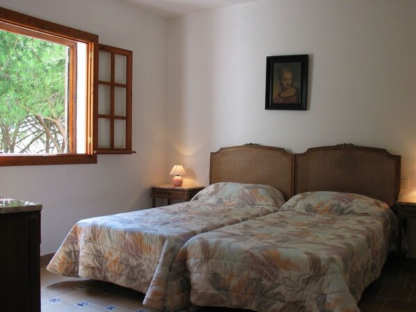 A bedroom with two beds, a window, a lamp, and a framed picture on the wall. - 2 bedroom apartment, Roche (Roche)