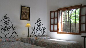 A room with two beds, a lamp, a painting, and a window with bars. - 2 bedroom apartment, Roche (Roche)