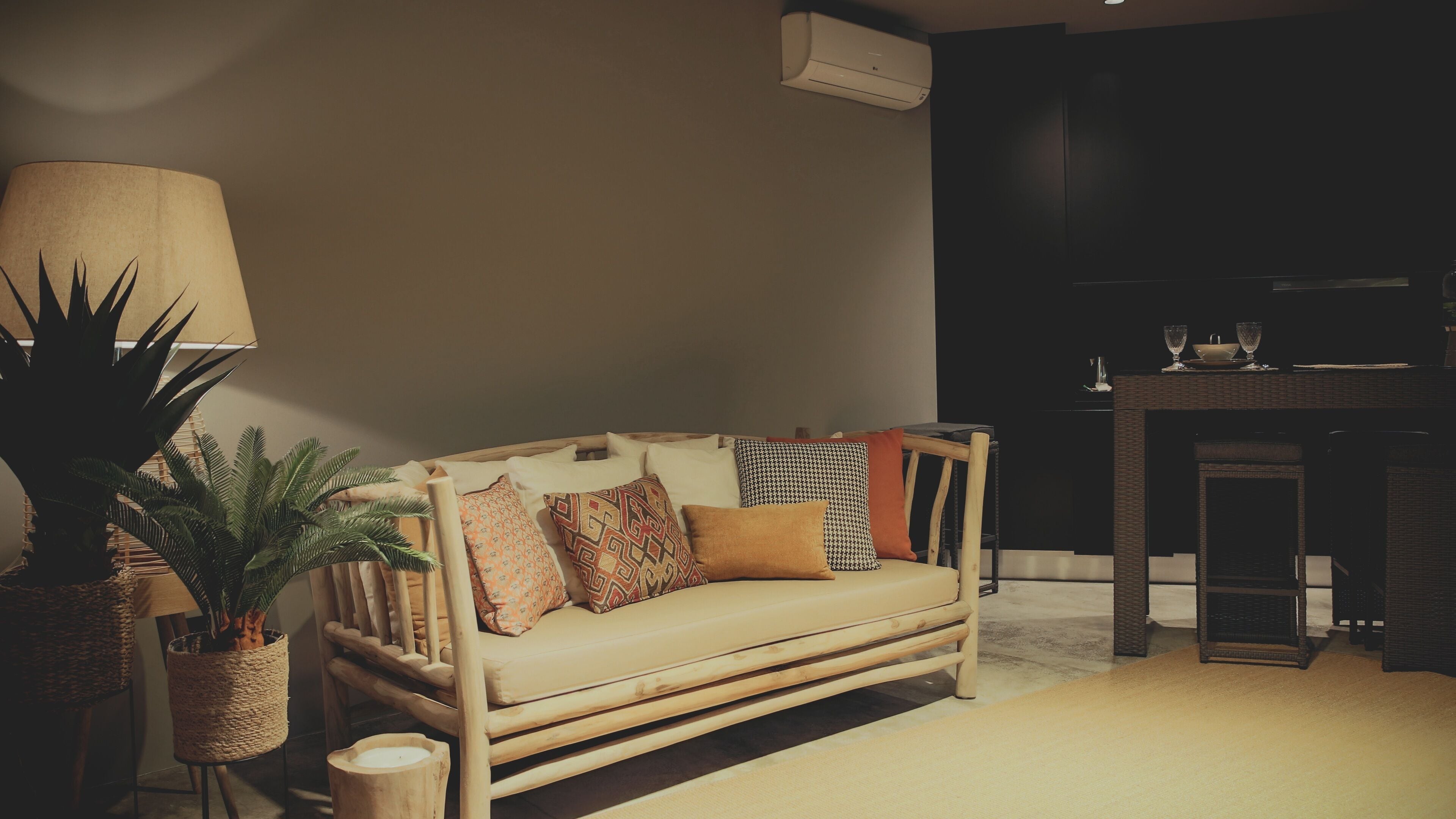 A cozy living room with a wooden sofa, a potted plant, and a lamp.