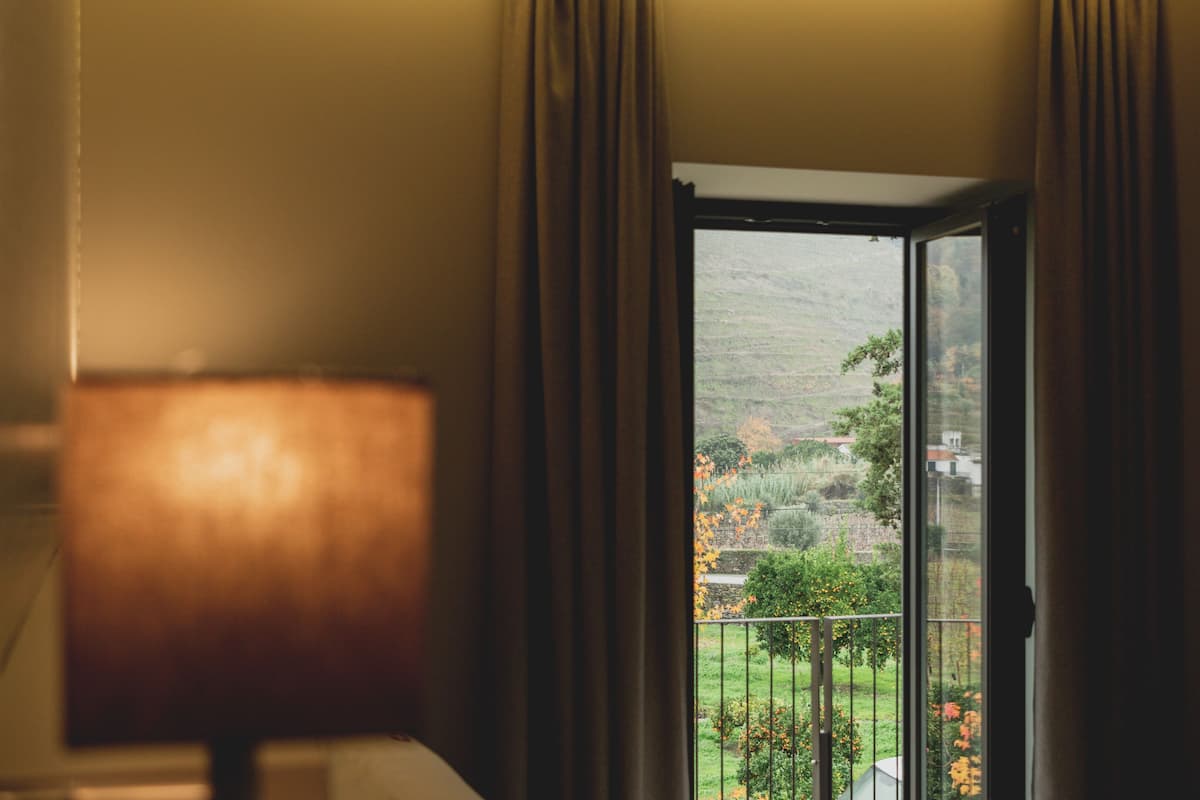 Quarto com janela dando para um jardim e colinas.