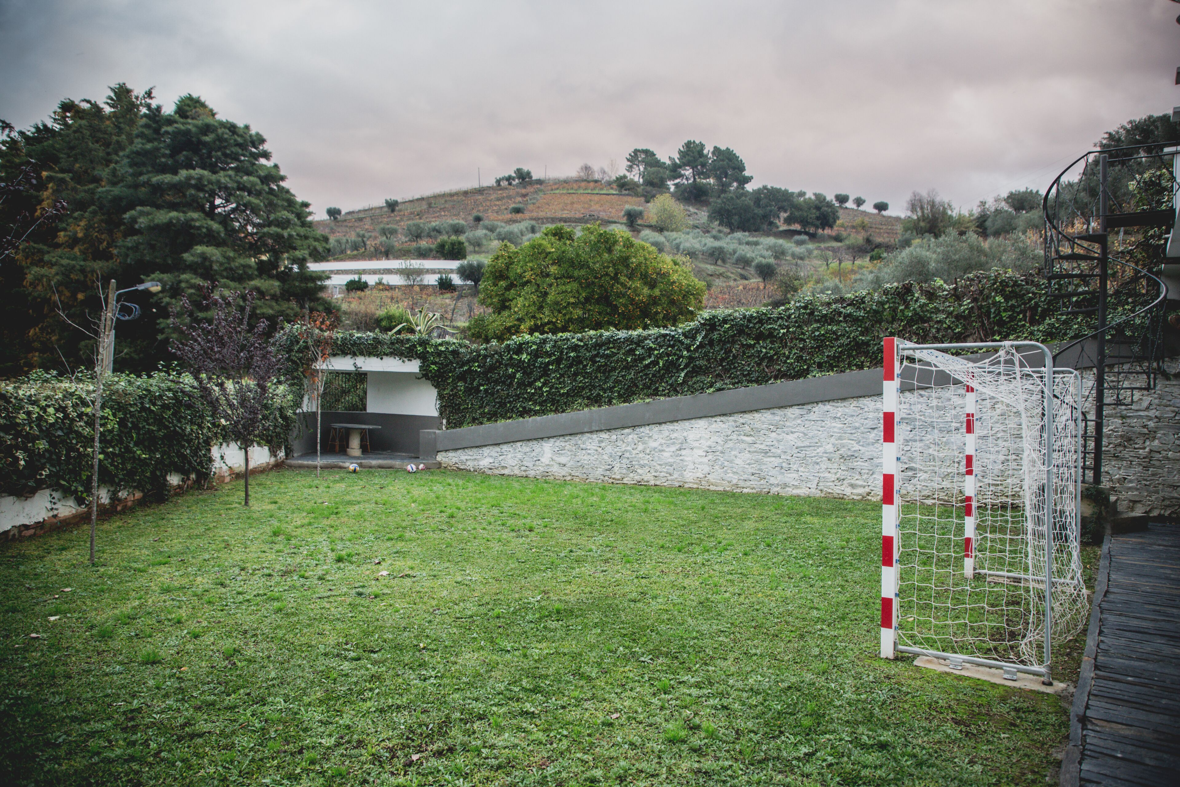 A grassy outdoor area with a goalpost and a stone wall.