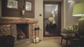 A cozy room with a stone fireplace, framed pictures on the wall, a door leading to another area, and a lamp on a side table. - Casal dos Capelinhos - Quinta Nova (Santa Marta de Penaguião)