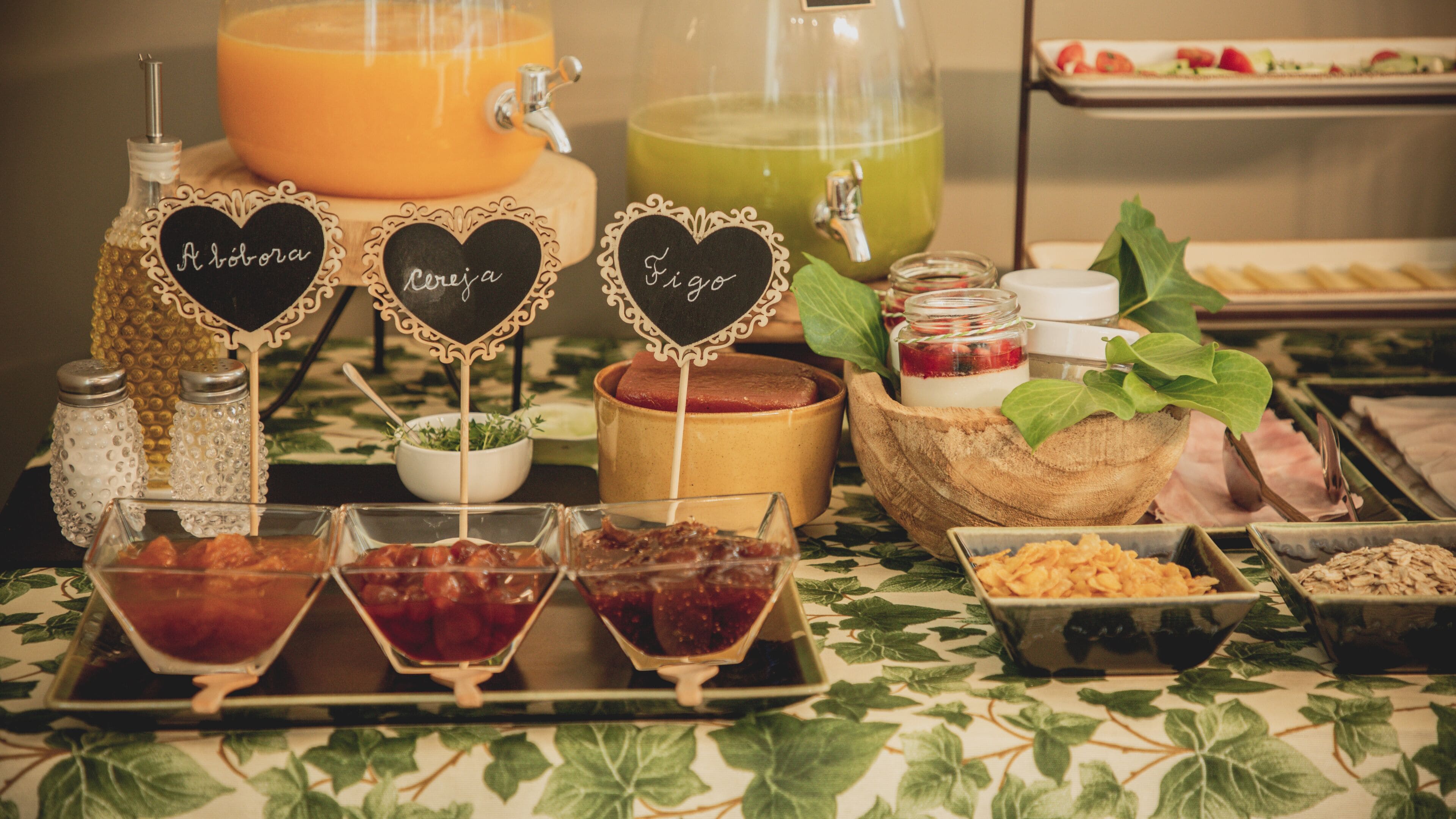 Un tavolo per buffet con diversi articoli di cibo, tra cui un distributore arancione per bevande, un distributore verde per bevande e diverse ciotole di cibo.