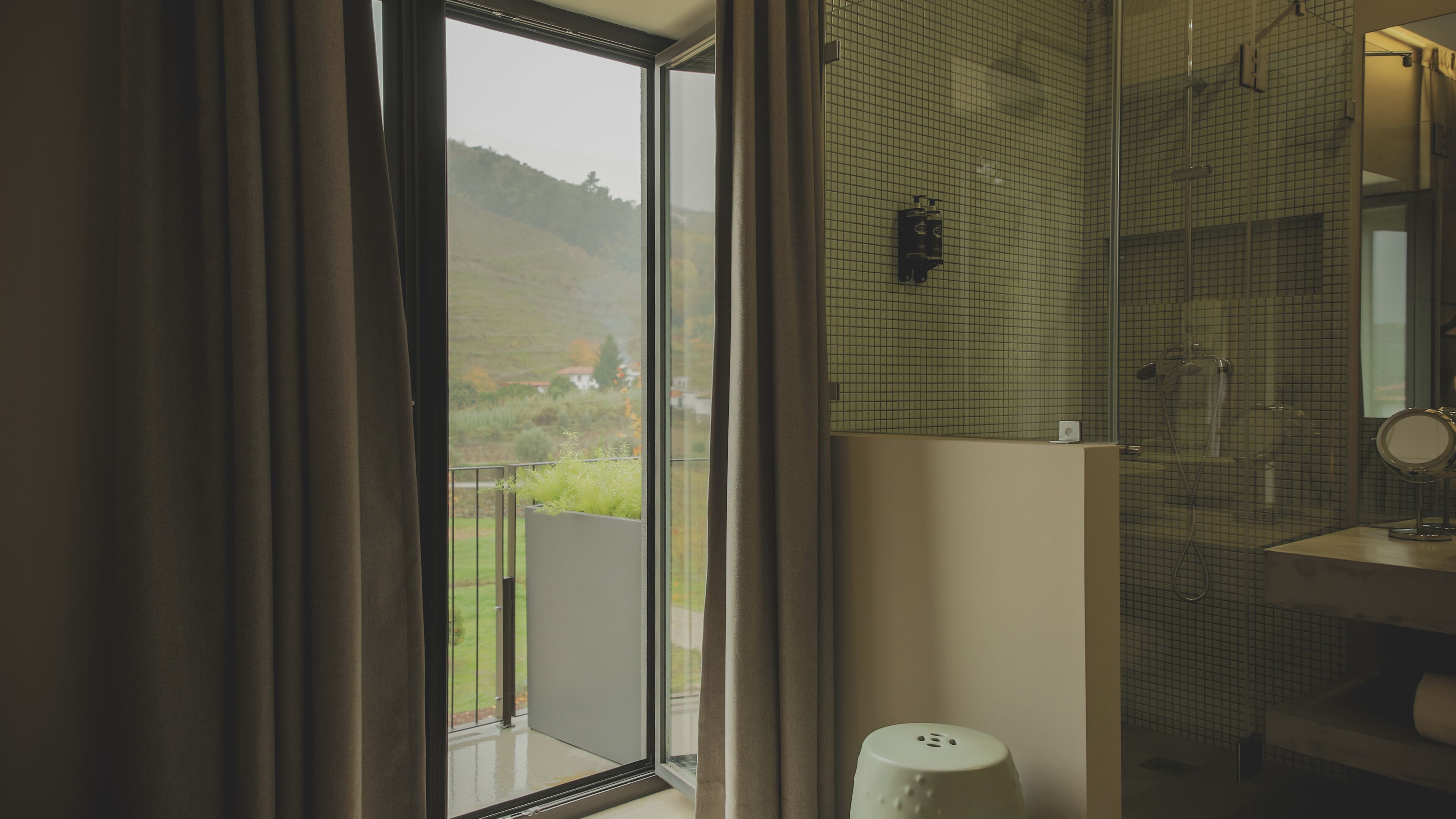 A bathroom with a large window, a shower, and a mirror.