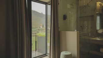 A bathroom with a large window, a shower, and a mirror.