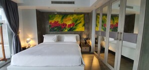 Une chambre d’hôtel avec un grand lit, une armoire avec des miroirs, un tableau au mur et une table de chevet avec une lampe.