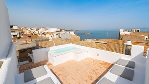 A rooftop terrace with a swimming pool, white walls, and a view of the sea and town. - Florida: Stylish Downtown Duplex with Sea Views (L'Escala)