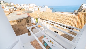 A rooftop terrace with a dining table and chairs, overlooking a coastal town and the sea. - Florida: Stylish Downtown Duplex with Sea Views (L'Escala)