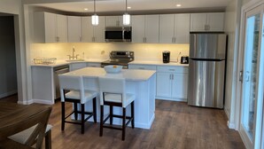 Una cocina moderna con armarios blancos, electrodomésticos de acero inoxidable e iluminación colgante.