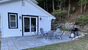 Una casa con patio, mobiliario exterior y una parrilla.
