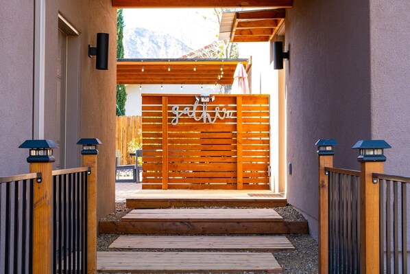 Un cancello di legno con un cartello che dice 'gather', che dà accesso a un pontile in legno con delle scale.