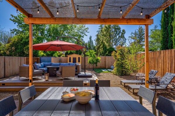 A covered patio area with outdoor furniture, a dining table, and a red umbrella.