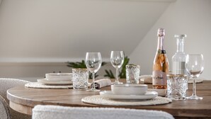 Une table à manger dressée avec de l’argenterie blanche, de la verrerie transparente et une bouteille de vin de la région de Côte de Paris.