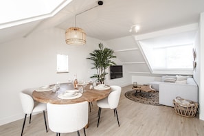 Un comedor moderno con una mesa de madera, sillas blancas y una lámpara colgante.