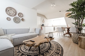 Una sala de estar moderna con un sofá gris, una mesa de centro de madera y una alfombra estampada.