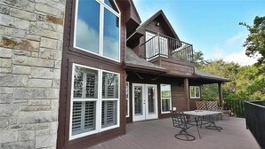 A two-story house with a deck, large windows, and a balcony. - CL 1181 Cypress Ridge (Canyon Lake)