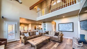 A spacious living area with a large sectional sofa, a wooden coffee table, and a staircase leading to an upper level. - CL 1181 Cypress Ridge (Canyon Lake)
