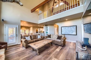 A spacious living area with a large sectional sofa, a wooden coffee table, and a staircase leading to an upper level. - CL 1181 Cypress Ridge (Canyon Lake)
