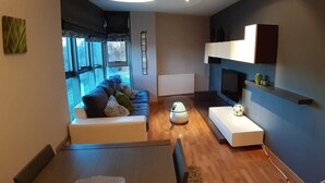 Un salon moderne avec un canapé, une table basse, un téléviseur et une cheminée.