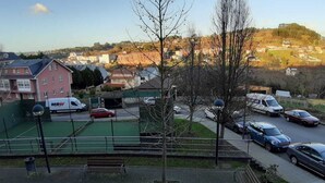 Un quartier résidentiel avec des maisons, un terrain de sport verdoyant et une route bordée de voitures garées.