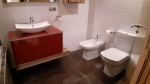 Une salle de bain avec un meuble-lavabo rouge, un lavabo blanc, un bidet et des toilettes.