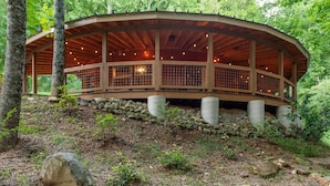 Une cabane en bois avec un toit incurvé, de grandes fenêtres et des fondations en pierre.