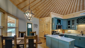 Un intérieur en bois comprenant un coin repas, une cuisine et un grand îlot central.