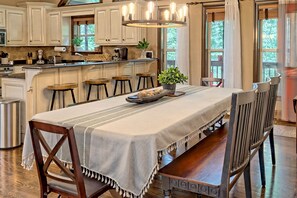 Una cocina amplia con una isla grande, sillas de madera y una mesa de comedor preparada para cuatro.
