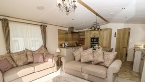 A living room with two sofas, a coffee table, and a chandelier. - Crosswinds 68 (Bembridge)