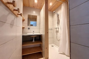 A bathroom with a wooden vanity, a sink, a mirror, and a shower with a curtain.