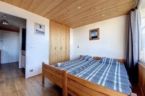 Un dormitorio con una cama y techo de madera, y un ventanal con cortinas.