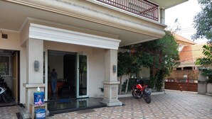 A building with a covered entrance, a motorcycle parked outside, and a tiled patio area.