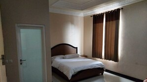 A bedroom with a bed, a door, a window with curtains, and a tiled floor.