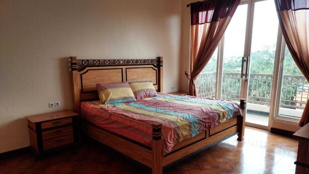 A bedroom with a wooden bed, a nightstand, a dresser, and a balcony with curtains.