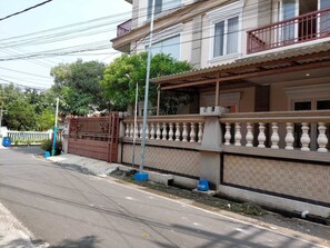 Un edificio residencial con entrada porticada, un balcón con barandilla y una calle en la parte delantera.