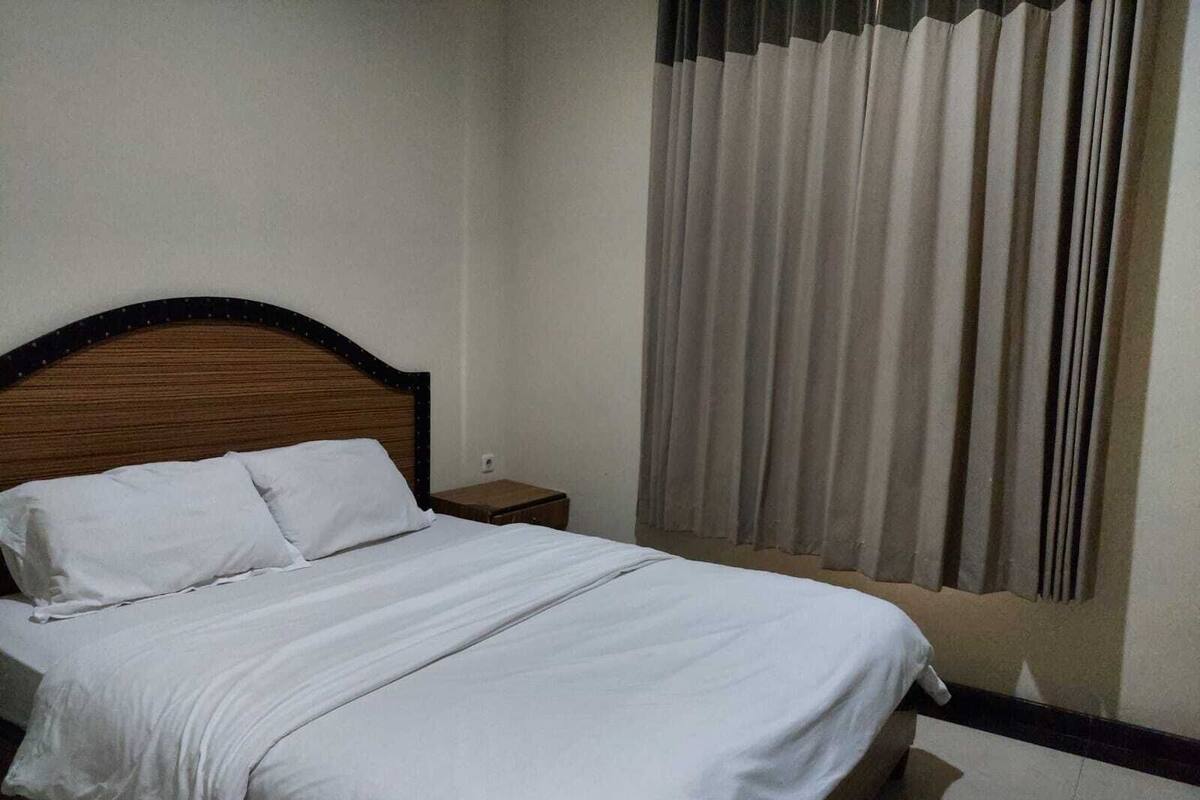 Een net opgemaakt bed met witte lakens in een hotelkamer.