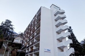 Un hotel a più piani con balconi, un cartello per ristorante e pizzeria e un segnale che indica parcheggio privato.