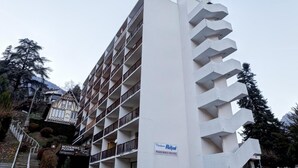 A multi-story hotel with balconies, a sign for a restaurant and pizzeria, and a sign indicating private parking. - 50m from resort center, 2nd floor, view mountain, balcony, parking, tv, 29m², Brides Les Bains (Brides-les-Bains)