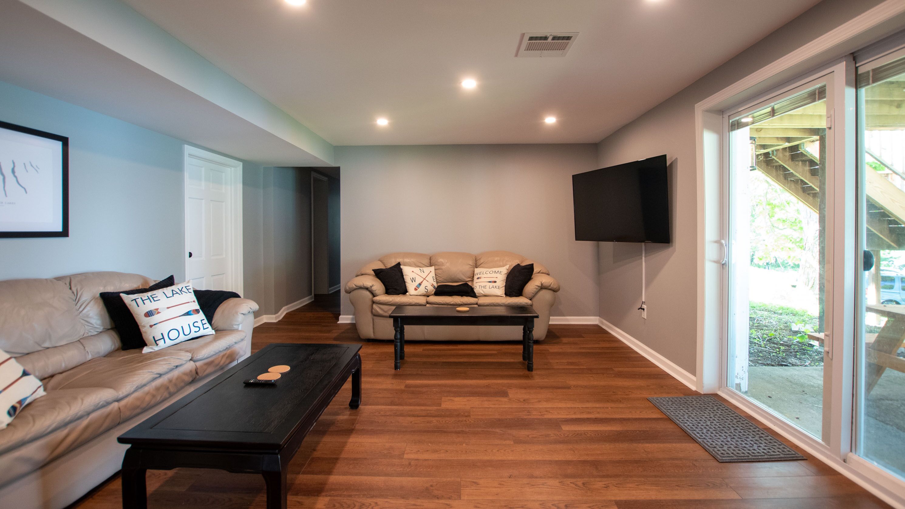 A living room with a sofa, a coffee table, and a TV mounted on the wall.