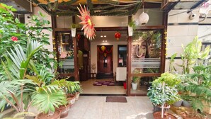 Entrada de hotel com design tradicional, plantas em vasos de cada lado e um tapete decorativo.