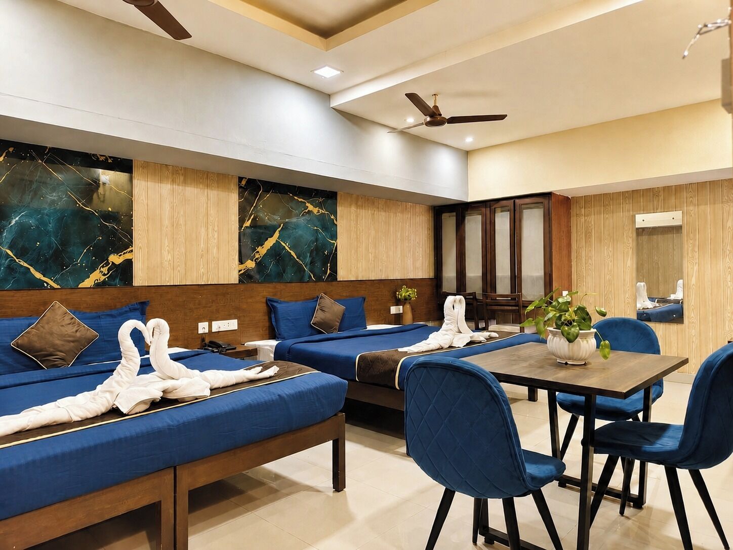 A hotel room with a large bed, a dining table with chairs, and a mirror.