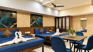 Una habitación de hotel con una cama grande, una mesa de comedor con sillas y un espejo.