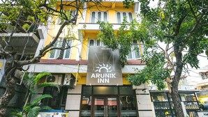 Um edifício com uma placa indicando 'Arunik Inn', exibindo um símbolo de sol.