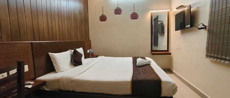 Habitación de hotel con cama, cabecero de madera, mesita de noche, televisor montado en la pared y un espejo.