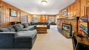 A log cabin interior with a sectional sofa, a fireplace, and wooden walls.