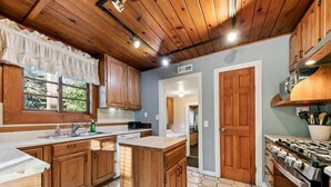 A kitchen with wooden cabinets, a sink, a dishwasher, and a stove.