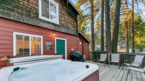 A spa cabin with a hot tub, deck chairs, and a green door.