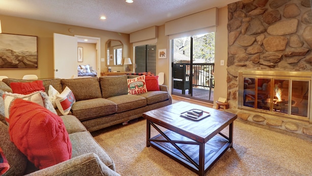 A cozy living room with a stone fireplace, a sofa, and a coffee table.