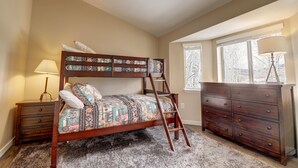 A bedroom with a bunk bed, a dresser, a lamp, and a window with a view. - 201 Point Drive 2 Bedroom Condo by RedAwning (Frisco)